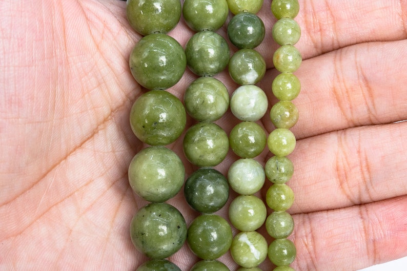 May include: A strand of green jade beads of varying sizes, arranged in a graduated pattern. The beads are smooth and polished, with a subtle sheen.