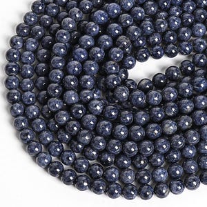 Op de afbeelding: Een streng donkerblauwe ronde edelsteen kralen. De kralen zijn glad en gepolijst en hebben een licht gespikkeld uiterlijk.