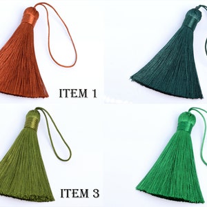 May include: Four colorful tassels in shades of orange, dark green, olive green, and bright green. Each tassel has a matching loop and a wrapped top. The text "ITEM" followed by a number is printed next to each tassel.