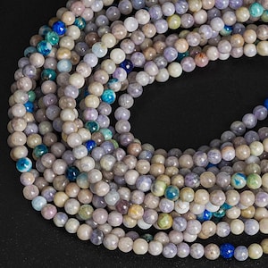 May include: A strand of round, light purple, gray, and white gemstone beads. The beads have a mottled, cloudy appearance.