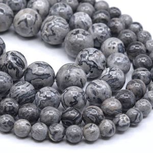 May include: A strand of gray and black marbled round beads. The beads are smooth and polished.