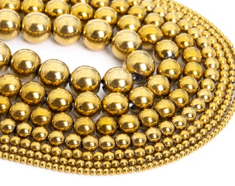 May include: A collection of gold-toned metal beads of various sizes, arranged in a circular pattern. The beads are smooth and shiny, with a metallic finish.