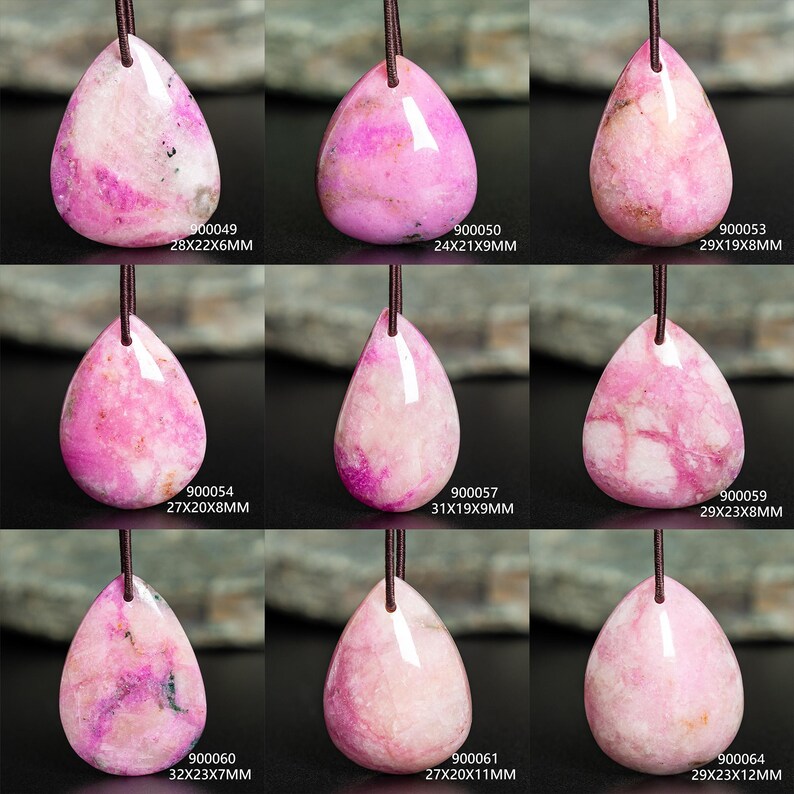 May include: Nine teardrop-shaped pink stone pendants on dark cords. Each pendant features unique white and magenta marbling. Labels include codes and dimensions: 900049 28x22x6mm, 900050 24x21x9mm, 900053 29x19x8mm, 900054 27x20x8mm, 900057 31x19x9mm, 900059 29x23x8mm, 900060 32x23x7mm, 900061 27x20x11mm, and 900064 29x23x12mm.