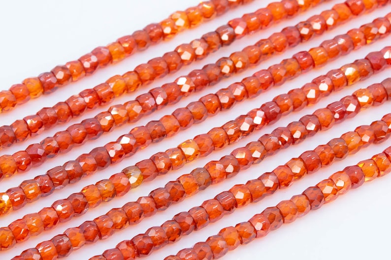 May include: A strand of orange carnelian beads, each bead is faceted and has a square shape.