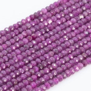 May include: A strand of faceted purple gemstone beads. The beads are round and have a slightly irregular shape. They are strung on a clear thread.