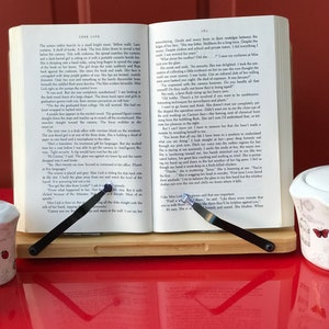 May include: A wooden book stand with two black metal page holders holding open a book with the title "Lark Love".  Two small white salt and pepper shakers with a butterfly design are on the left side of the stand. A small white sugar bowl with a butterfly design is on the right side of the stand.