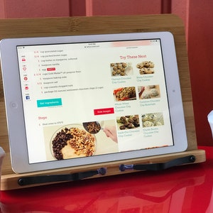 May include: A tablet displaying a recipe for chocolate chip cookies with a list of ingredients and steps. The tablet is on a wooden stand with a white ceramic sugar bowl and two salt shakers in the foreground. The recipe includes 1/4 cup granulated sugar, 1/2 cup packed brown sugar, 1 cup butter or margarine, softened, 1 teaspoon vanilla, 1 1/4 cups Gold Medal&reg; all-purpose flour, 1 teaspoon baking soda, 1/2 teaspoon salt, 1 cup coarsely chopped nuts, 1 package (12 oz) semisweet chocolate chips (2 cups).