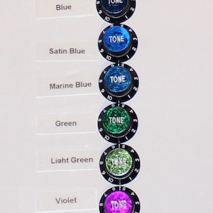 May include: A vertical column of eight circular guitar tone knobs, each featuring a black base with numbered markings from 1 to 10 and the word TONE printed in white. The center inserts display various colors: indigo, blue, satin blue, marine blue, green, light green, violet, and red.