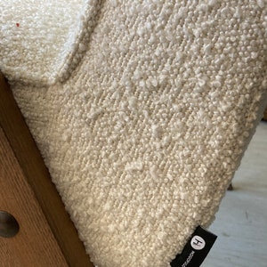 May include: Close-up of a white textured fabric chair with a black label that says "HOCOOCO" and a capital "H".