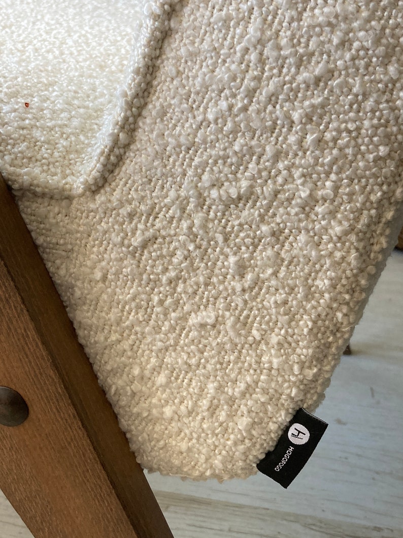 May include: Close-up of a white textured fabric chair with a black label that says "HOCOOCO" and a capital "H".
