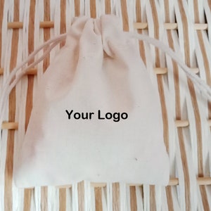 May include: A white cotton drawstring bag with the text "Your Logo" printed on the front.