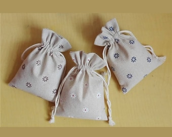 May include: Three small, beige drawstring bags with floral patterns. The bags are made of a natural fabric and have a rustic look.