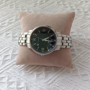 May include: A silver Citizen Eco-Drive watch with a black face and silver hands. The watch has Roman numeral hour markers and a date window at the 3 o'clock position.