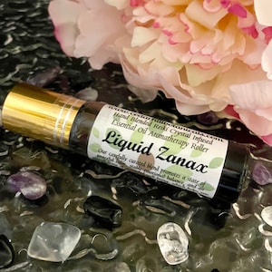 May include: A glass roller bottle with a gold cap and a label that reads "Liquid Zanax" and "Hand Blended Reiki Crystal Infused Essential Oil Aromatherapy Roller".