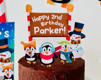 May include: A chocolate cake decorated with a penguin, snowman, and a sign that reads "Happy 2nd Birthday Parker!"