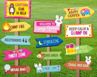 May include: A set of 12 colorful wooden signs with arrows pointing in different directions. The signs have various camping-themed phrases, such as "Camp Fire", "Happy Camper", "Keep Calm & Glamp On", and "S'more Love".