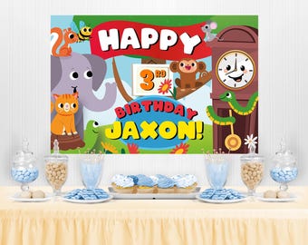 May include: A colorful birthday party banner with a jungle theme. The banner features a clock, animals, and the text "Happy 3rd Birthday Jaxon!"