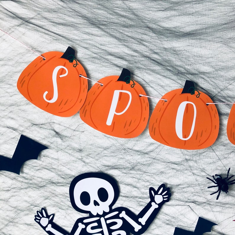 May include: Orange pumpkin-shaped paper cutouts strung together with twine to spell out "SPOOKY".