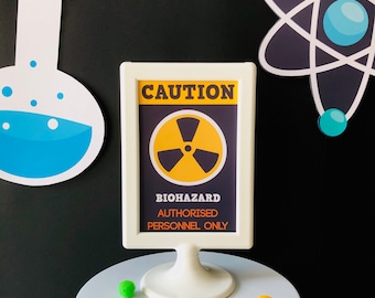 May include: A white sign with a black frame and the words "CAUTION" in yellow letters. The sign has a black and yellow biohazard symbol and the text "BIOHAZARD AUTHORISED PERSONNEL ONLY".
