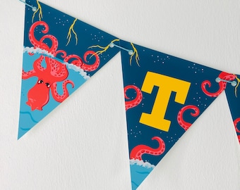 Könnte beinhalten: Ein blaues und rotes Partybanner mit einem Oktopus-Motiv und dem Buchstaben "T" in Gelb. Das Banner ist aus Filz und hat eine Schnur zum Aufhängen.