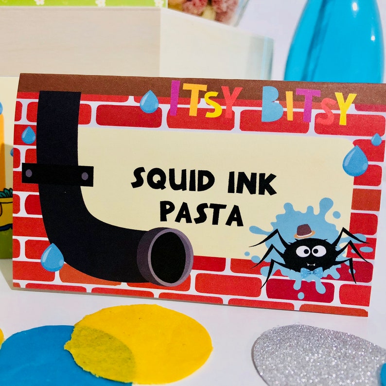 May include: A red, yellow, and brown food label with the text "Itsy Bitsy Squid Ink Pasta" and a cartoon spider with a blue bow tie.