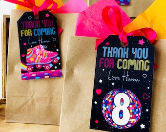 Può includere: Due sacchetti regalo di carta marrone con nastro rosa e rosso. Ogni sacchetto ha un'etichetta di ringraziamento con un design retrò. Un'etichetta presenta un pattino a rotelle con colori arcobaleno e rosa. L'altra etichetta presenta una palla da discoteca con un numero 8 bianco. Entrambe le etichette dicono "Grazie per essere venuto" e "Con affetto, Hanna".