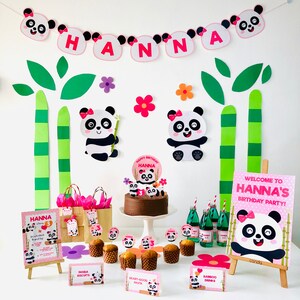 Op de afbeelding: Een roze en witte panda-thema verjaardagsfeest setup met een chocoladetaart, cupcakes en decoraties. De banner zegt "HANNA" en het bord zegt "Welkom op Hanna's verjaardagsfeest!"