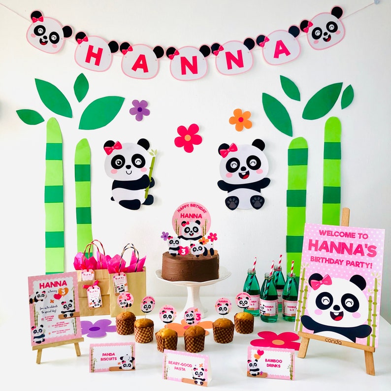 Op de afbeelding: Een roze en witte panda-thema verjaardagsfeest setup met een chocoladetaart, cupcakes en decoraties. De banner zegt "HANNA" en het bord zegt "Welkom op Hanna's verjaardagsfeest!"