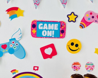 Può includere: Una collezione di decorazioni per feste colorate a tema gaming. Include un cartello rosa e blu "Game On!", forme di stelle e cuori, un arcobaleno e decorazioni per cupcake. Perfetto per una festa di compleanno.