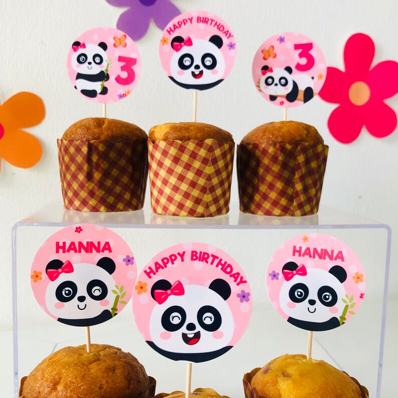 Op de afbeelding: Zes cupcakes met roze en witte pandabeer cupcake toppers. De toppers zeggen "Happy Birthday" en "Hanna" met een nummer "3" op sommige van hen.