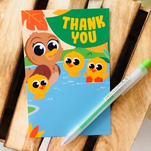 May include: A thank you card with a brown duck and three yellow ducklings in a blue pond. The card has green leaves and a brown and orange leaf in the background. The text "THANK YOU" is written in green letters on the card.
