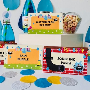 May include: A set of colorful printable food labels for a children's party. The labels feature a cartoon spider and the text "Itsy Bitsy" with different food names like "Watermelon Dessert", "Rain Puddle", and "Squid Ink Pasta".