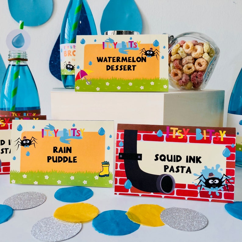 May include: A set of colorful printable food labels for a children's party. The labels feature a cartoon spider and the text "Itsy Bitsy" with different food names like "Watermelon Dessert", "Rain Puddle", and "Squid Ink Pasta".