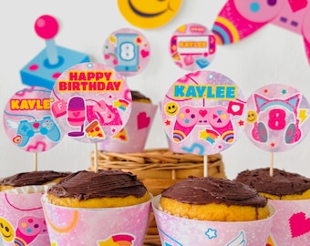 May include: Pink and blue cupcake toppers with a gamer theme. The toppers feature a game controller, headphones, a microphone, and a pizza slice. The text on the toppers reads "Happy Birthday" and "Kaylee".