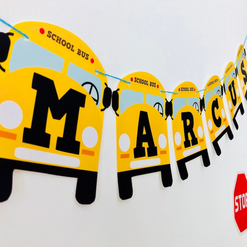 Close-up of Wheels on the Bus editable birthday banner garland with yellow school buses spelling MARCUS for toddler school bus themed party decoration