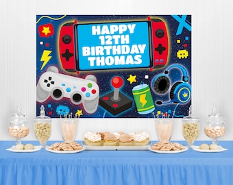 Może przedstawiać: Niebieski stół jest nakryty na przyjęcie urodzinowe o tematyce gier. Tło przedstawia czerwony design konsoli do gier z napisem "HAPPY 12TH BIRTHDAY THOMAS". Stół jest udekorowany smakołykami i przekąskami.