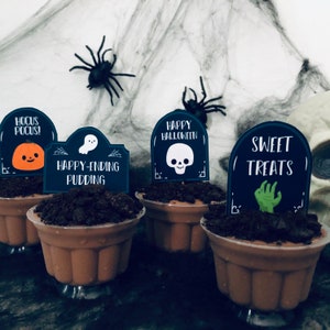 May include: Four chocolate pudding cups decorated with Halloween-themed tombstone toppers. The toppers feature a pumpkin, a ghost, a skull, and a zombie hand. The text on the toppers reads "Hocus Pocus!", "Happy-Ending Pudding", "Happy Halloween", and "Sweet Treats".