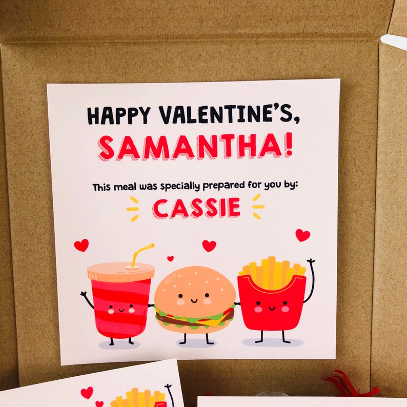 Pu&ograve; includere: Un biglietto di San Valentino con il messaggio "HAPPY VALENTINE'S, SAMANTHA!" e la scritta "This meal was specially prepared for you by: CASSIE". Il biglietto presenta illustrazioni di cartoni animati di una bevanda, un hamburger e patatine fritte.
