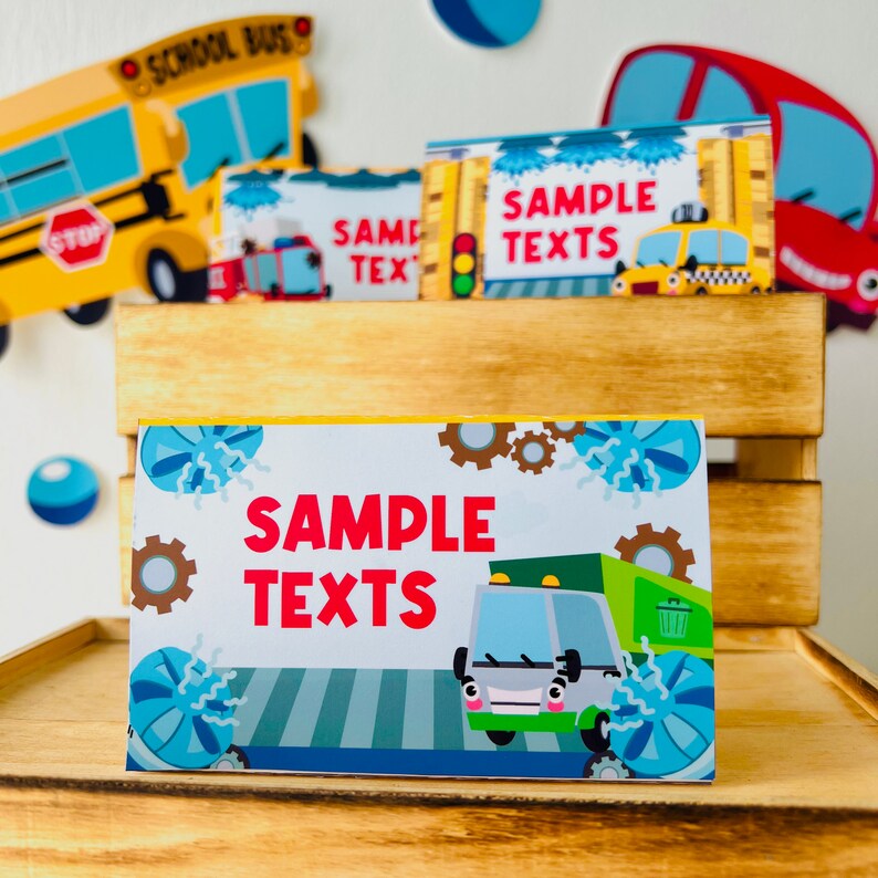 A set of printable party food tent cards featuring a colourful cartoon truck, green garbage truck, yellow taxi and red fire truck with the text "SAMPLE TEXTS", inside a car wash station.