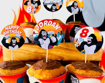 May include: A birthday party table setting with cupcakes decorated with chocolate frosting and topped with round edible images of a gorilla. The images feature the words "Happy Birthday" and "Jordan".