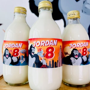 May include: Three clear glass bottles with white labels. The labels have a red, orange, and yellow background with a gorilla graphic and the text "Jordan is 8".