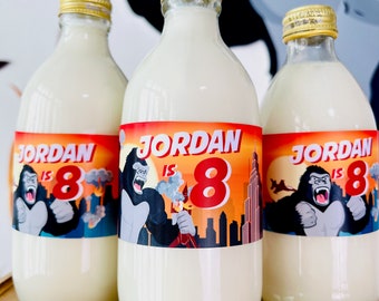 May include: Three clear glass bottles with white labels. The labels have a red, orange, and yellow background with a gorilla graphic and the text "Jordan is 8".