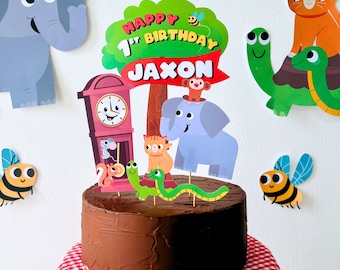 May include: A chocolate cake with a green, red, and yellow animal-themed cake topper. The topper says "Happy 1st Birthday Jaxon".