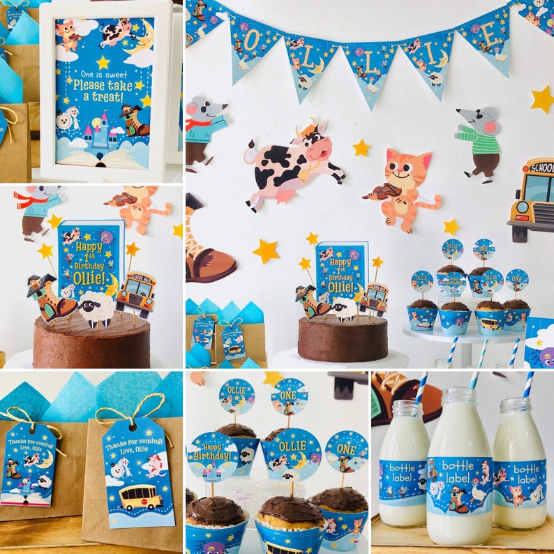 May include: A first birthday party setup with a blue and white color scheme. The decorations feature a school bus, farm animals, and stars. There are cupcakes with toppers that say "Ollie" and "One". There are also favor bags with tags that say "Thanks for coming, Love, Ollie".