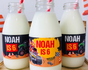 May include: Three glass milk bottles with labels featuring a monster truck design. The labels are black, yellow, and orange with the text "Noah is 6".