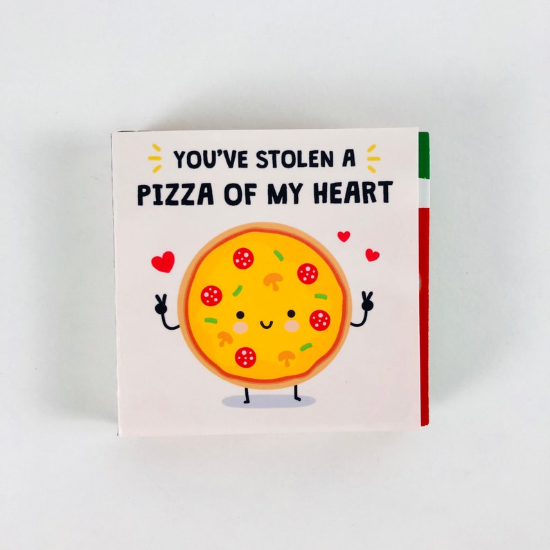 Pu&ograve; includere: Biglietto quadrato con un'illustrazione di pizza a cartoni animati. La pizza ha una faccia sorridente, salame, funghi e peperoni verdi. Il testo recita "YOU'VE STOLEN A PIZZA OF MY HEART".