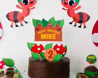 May include: A chocolate cake decorated with a wooden sign that says "Happy Birthday Mike" and a number 2 surrounded by green leaves and red mushrooms. The cake is decorated with two cartoon ants wearing green helmets.