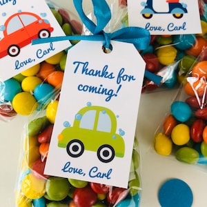 May include: A green car with blue bubbles on a white tag with the text "Thanks for coming!" and "love, Carl". The tag is attached to a clear bag filled with colorful candy.