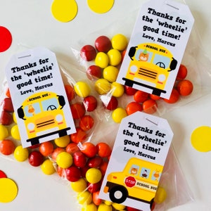 May include: Three yellow school bus favor tags with a giraffe, zebra, and lion on each bus. The tags say "Thanks for the 'wheelie' good time! Love, Marcus" and have a red stop sign. Each tag is attached to a clear plastic bag filled with orange and yellow candy.