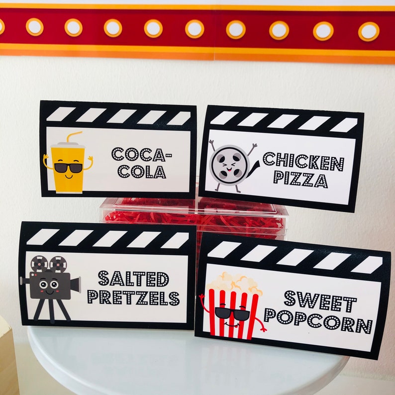 Concession Tickets and Food Tent Cards for Movie Night Party, clapperboard style popcorn labels and drink cards printable. The signs read "Coca-Cola", "Chicken Pizza", "Salted Pretzels", and "Sweet Popcorn".